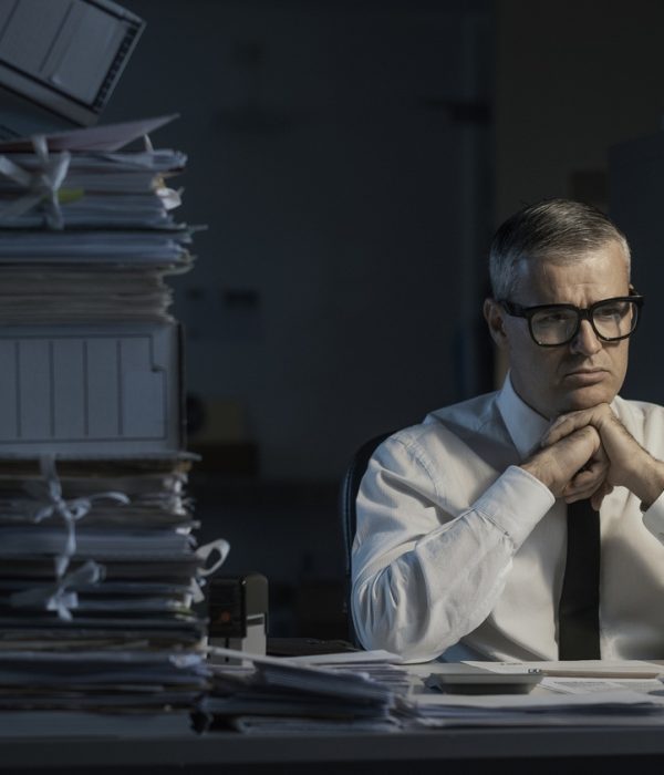 Pensive businessman overloaded with paperwork